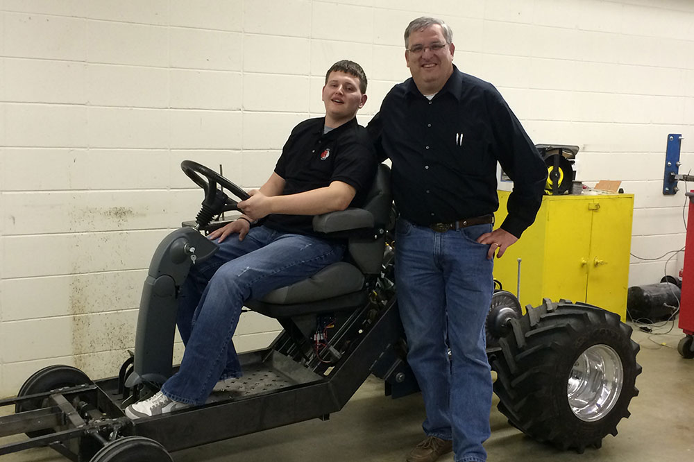 With his family and caregivers along, Caleb navigated in a wheelchair to the Quarter Scale Team’s workspace in the Splinter Labs, part of UNL’s Tractor Test Lab facilities at East Campus. The team gathered to show Caleb their progress during the winter months, and soon the students brought the 2014 tractor to the test track outside. With excitement and enthusiasm they lifted Caleb into the driver’s seat, and team members flanked both sides of the tractor as Caleb took the creation for a short drive.